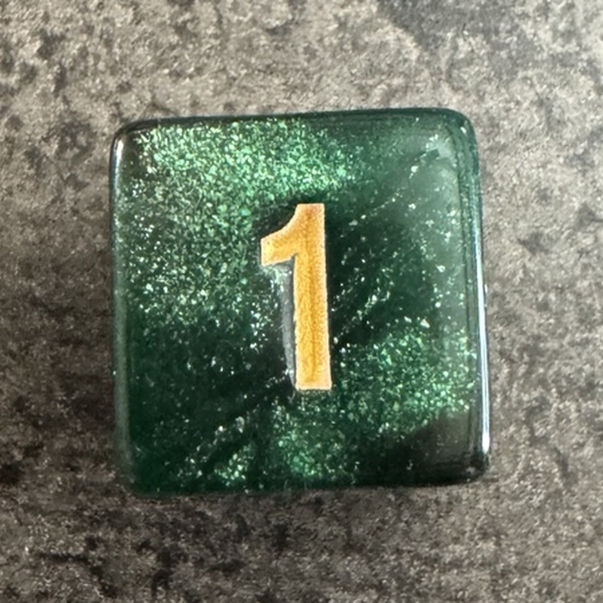 Dé D6 vert pailleté, chiffres dorés, vendu à l'unité — photo réelle. / Green glitter D6 with gold numerals, sold individually — actual photo.