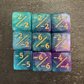 Photo réelle recadrée : 9 dés compteurs négatifs turquoise, bleu et violet pailletés. / Cropped original photo: 9 turquoise, blue and purple glitter negative counter dice.