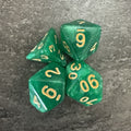 Lot de 4 dés polyédriques verts pailletés, chiffres dorés. Photo réelle recadrée. / Assortment of 4 green glitter polyhedral dice with gold-coloured numbers. Cropped original photo.