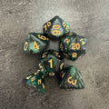 Lot de 6 dés polyédriques vert et noir pailletés, chiffres dorés, sans D6. Photo réelle recadrée. / Set of 6 green and black glitter polyhedral dice with gold-coloured numbers; no D6 included.