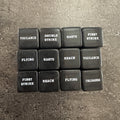 Lot de 12 dés noirs de capacités avec inscriptions blanches en anglais. Photo réelle recadrée. / Set of 12 black keyword dice with white English text. Cropped original photo.