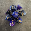 Lot de 8 dés polyédriques pailletés bleu, violet et noir, chiffres dorés. Photo réelle. / Assortment of 8 blue, purple and black glitter polyhedral dice with gold-coloured numbers.