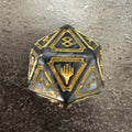 Dé D20 géant Magic Les Secrets de Strixhaven Codex Bundle, noir et gris avec ornements triangulaires dorés — photo réelle. / Secrets of Strixhaven Codex Bundle oversized D20 — actual photo.