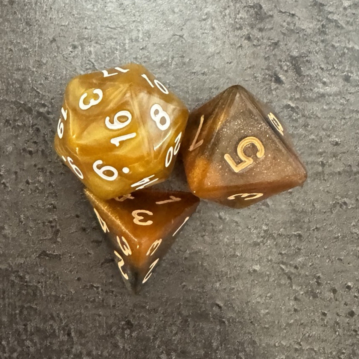 Lot réel de 3 dés ambrés : D4, D8 et D20, chiffres blancs et dorés. / Actual amber D4, D8 and D20 dice assortment.